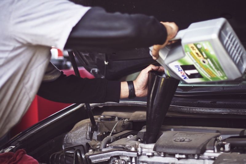 A mechanic in a workshop inspecting the underside of a car raised on a lift