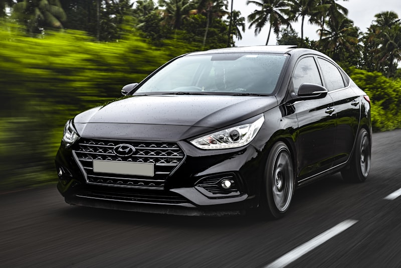 A car's headlights illuminating a dark road at night with the glow of taillights ahead